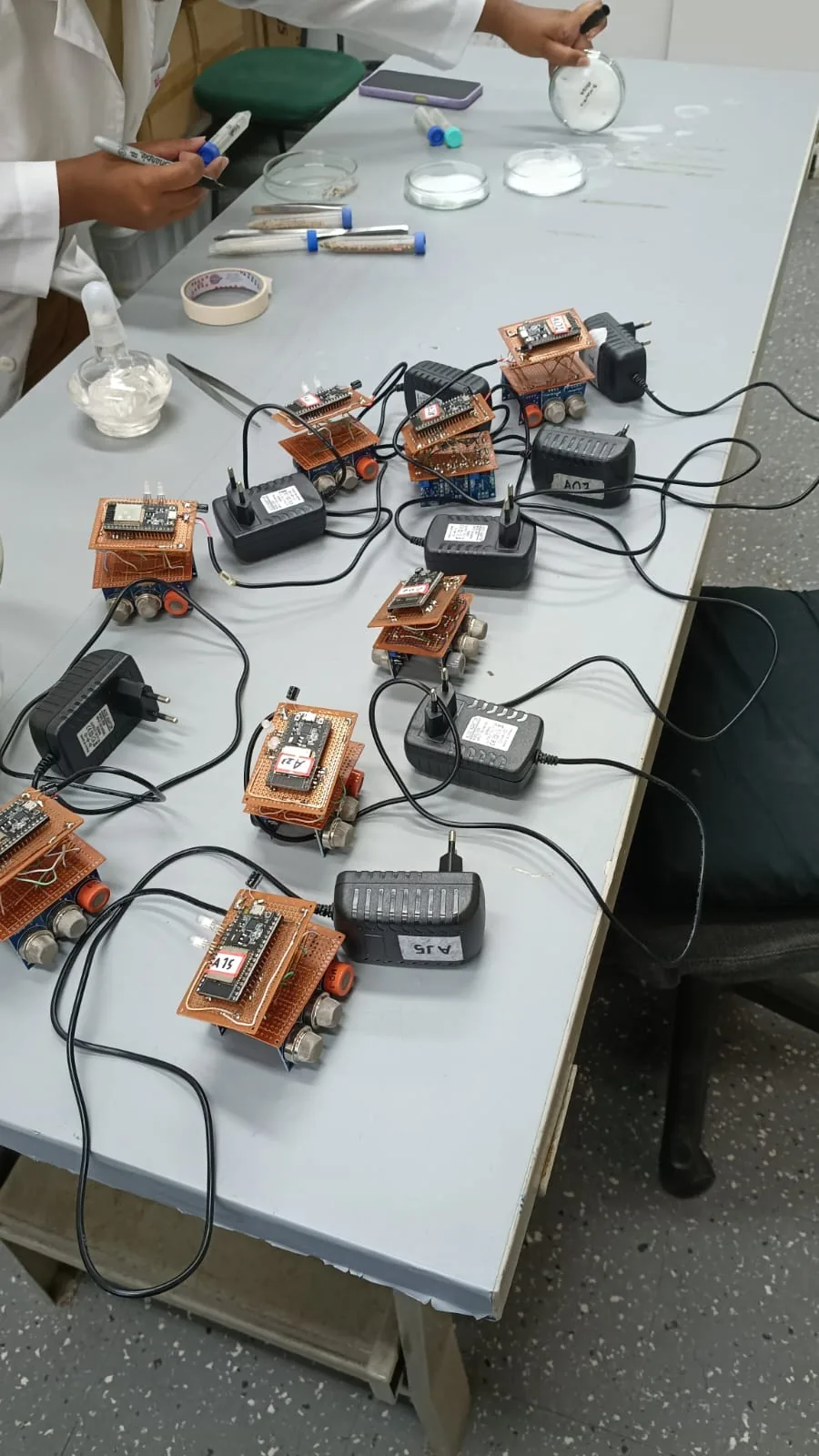Diversos protótipos eletrônicos organizados sobre uma bancada durante atividade de laboratório